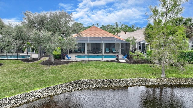 rear view of property featuring a lanai, a lawn, and a water view