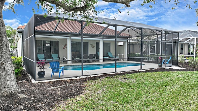 rear view of property featuring a lanai, a patio area, and a lawn