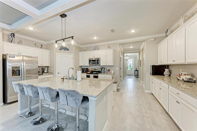 kitchen with white cabinets, an island with sink, light stone countertops, and appliances with stainless steel finishes