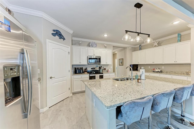 kitchen featuring light stone countertops, white cabinets, stainless steel appliances, sink, and a kitchen island with sink