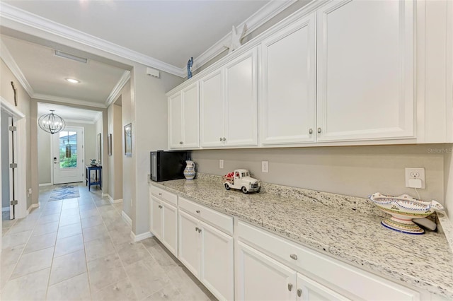 kitchen featuring white cabinets, ornamental molding, and light stone countertops