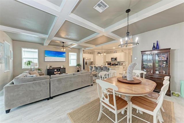 dining space featuring coffered ceiling, plenty of natural light, ceiling fan with notable chandelier, and beamed ceiling