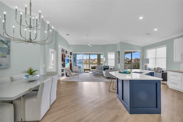 kitchen with sink, light hardwood / wood-style flooring, white cabinetry, a center island with sink, and a kitchen bar