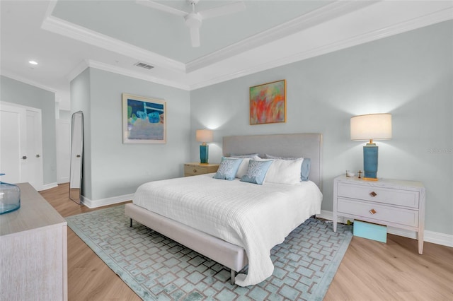 bedroom with a raised ceiling, crown molding, ceiling fan, and light hardwood / wood-style floors