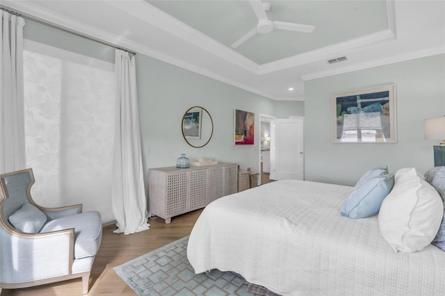 bedroom featuring a raised ceiling, ornamental molding, hardwood / wood-style floors, and ceiling fan