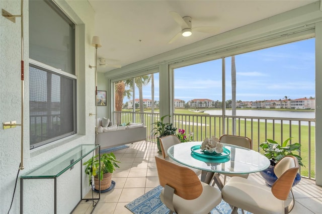 sunroom / solarium featuring a water view and ceiling fan