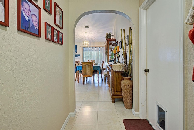 corridor with a chandelier and light tile patterned floors