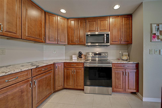 kitchen featuring light tile patterned flooring, light stone countertops, and appliances with stainless steel finishes