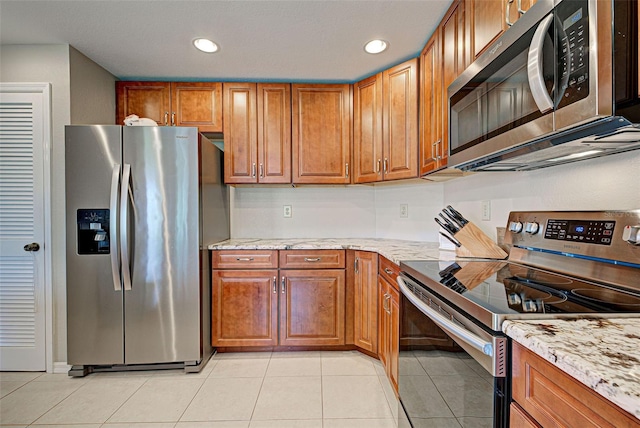 kitchen featuring light tile patterned floors, light stone countertops, and appliances with stainless steel finishes