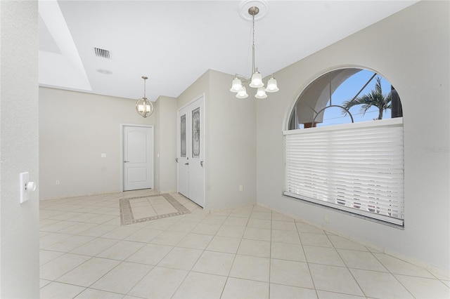 spare room featuring light tile patterned flooring and an inviting chandelier