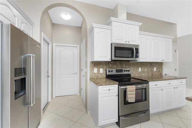 kitchen featuring white cabinetry, decorative backsplash, dark stone counters, and appliances with stainless steel finishes