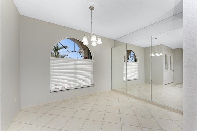 tiled spare room with an inviting chandelier