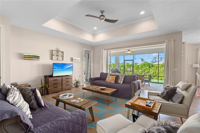 living room featuring ornamental molding, ceiling fan, and a tray ceiling