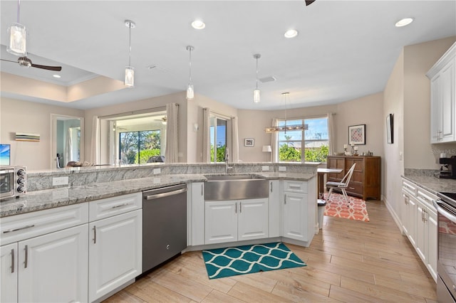 kitchen featuring sink, white cabinetry, hanging light fixtures, stainless steel dishwasher, and ceiling fan