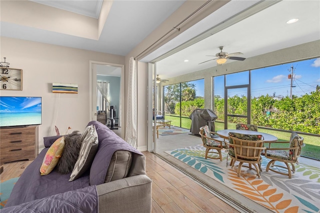 living room featuring ornamental molding, ceiling fan, and light wood-type flooring