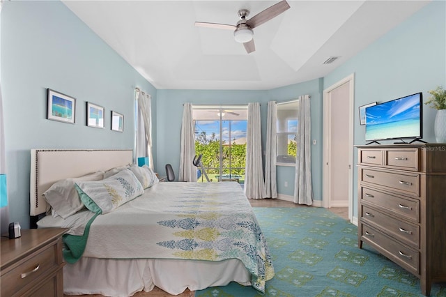 bedroom with a raised ceiling, light carpet, access to outside, and ceiling fan