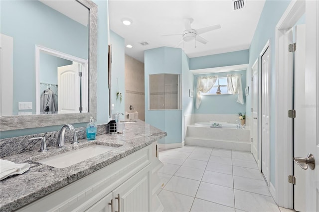 bathroom with tile patterned flooring, vanity, ceiling fan, and a tub to relax in