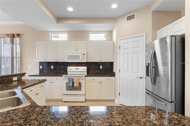 kitchen with white appliances, white cabinets, dark stone counters, and tasteful backsplash