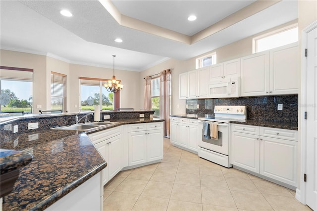 kitchen with white appliances, a notable chandelier, tasteful backsplash, a tray ceiling, and white cabinetry