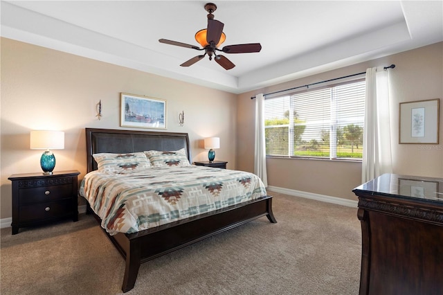 bedroom featuring ceiling fan, a tray ceiling, and light colored carpet