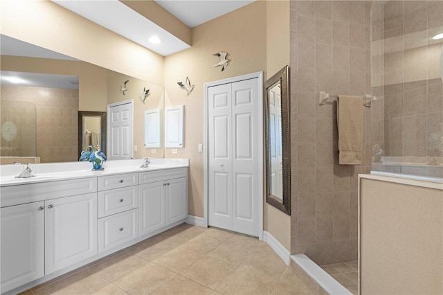 bathroom featuring tile patterned flooring, a tile shower, and vanity