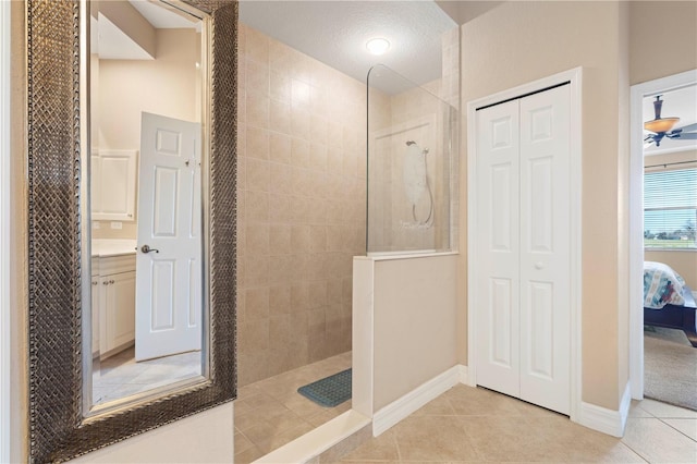 bathroom featuring tiled shower, vanity, tile patterned floors, ceiling fan, and a textured ceiling