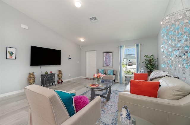 living room featuring vaulted ceiling, light hardwood / wood-style flooring, and a wood stove