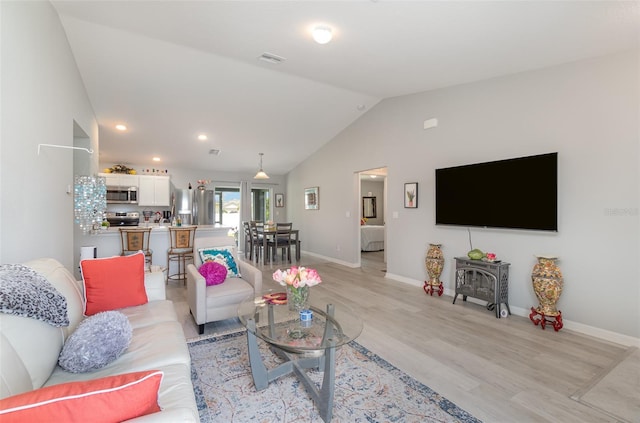 living room featuring lofted ceiling and light hardwood / wood-style flooring