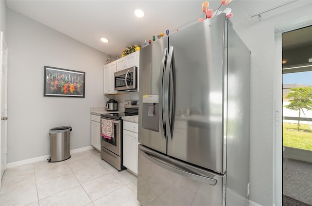 kitchen with appliances with stainless steel finishes, white cabinets, vaulted ceiling, and light tile patterned floors