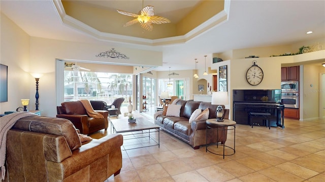 living room featuring ceiling fan, ornamental molding, and a tray ceiling