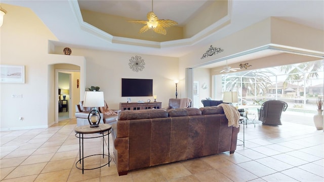 living room with a raised ceiling, ceiling fan, light tile patterned flooring, and ornamental molding