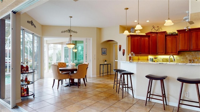 kitchen featuring decorative light fixtures, light stone countertops, light tile patterned flooring, and tasteful backsplash