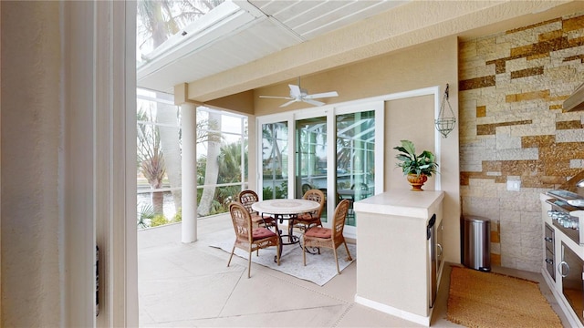 sunroom featuring ceiling fan, plenty of natural light, and decorative columns