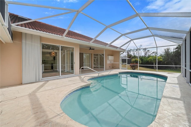 view of swimming pool featuring ceiling fan, glass enclosure, and a patio