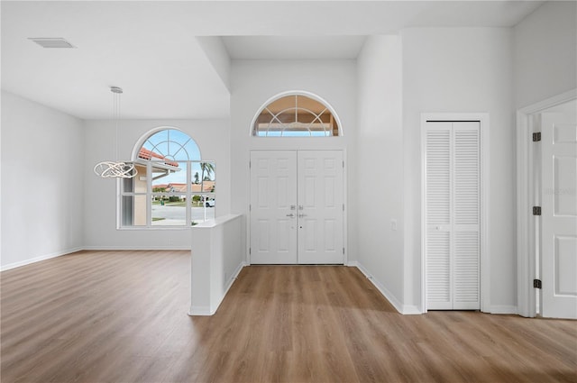 entrance foyer featuring light hardwood / wood-style floors, a notable chandelier, and a towering ceiling