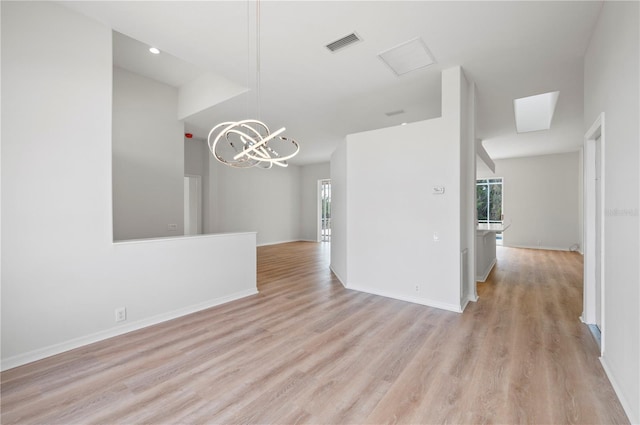 empty room with light wood-type flooring and a chandelier