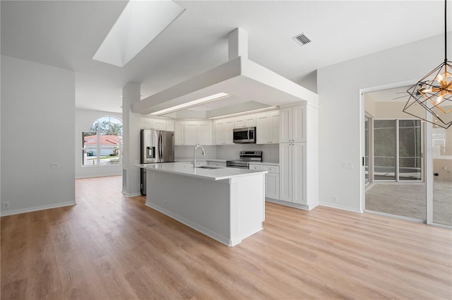 kitchen with decorative light fixtures, white cabinets, an island with sink, a notable chandelier, and appliances with stainless steel finishes