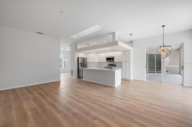 kitchen with decorative light fixtures, stainless steel appliances, a notable chandelier, light wood-type flooring, and white cabinets