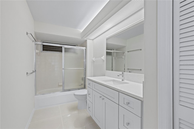 full bathroom with combined bath / shower with glass door, tile patterned flooring, vanity, and toilet