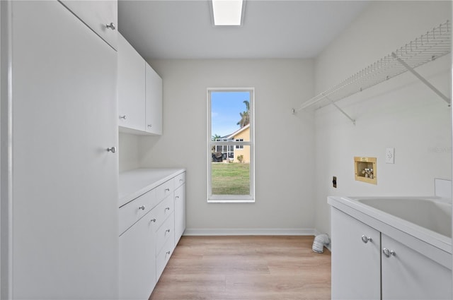 laundry room with hookup for an electric dryer, light hardwood / wood-style floors, hookup for a washing machine, cabinets, and sink