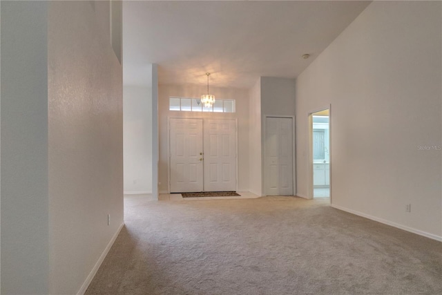 carpeted entryway featuring a high ceiling and a notable chandelier