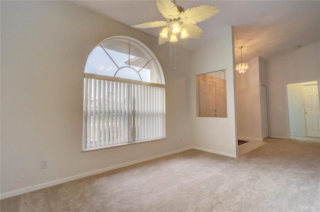 carpeted spare room featuring lofted ceiling and ceiling fan with notable chandelier