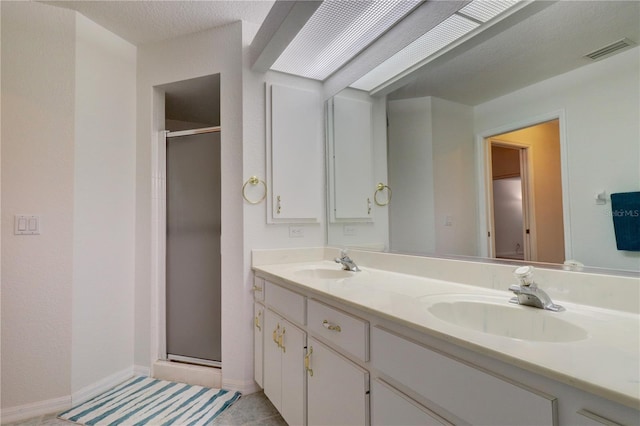 bathroom with a shower with door, vanity, and tile patterned floors