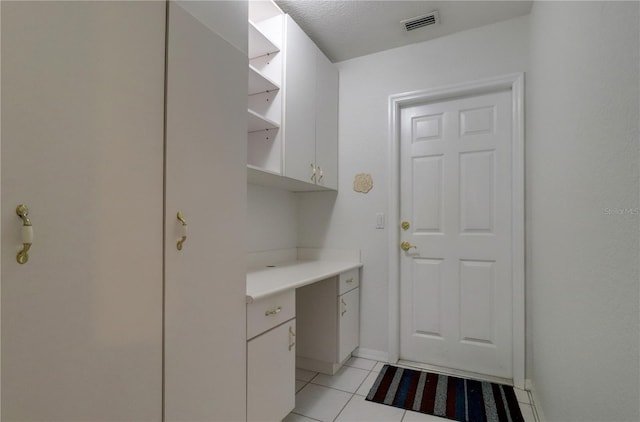 laundry area with a textured ceiling and light tile patterned floors