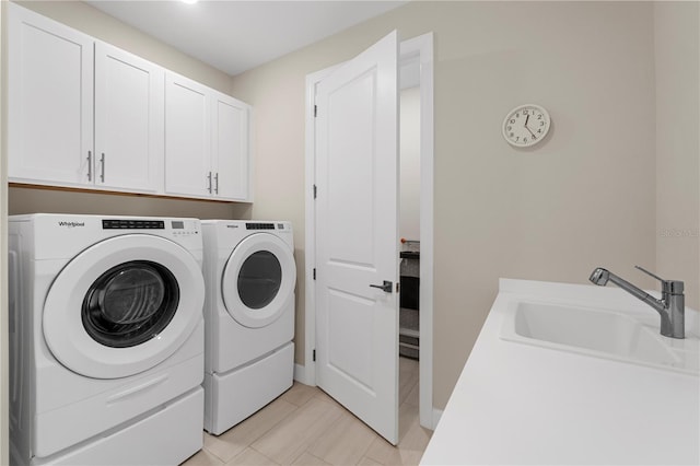 laundry area featuring cabinets, light tile patterned floors, washer and clothes dryer, and sink