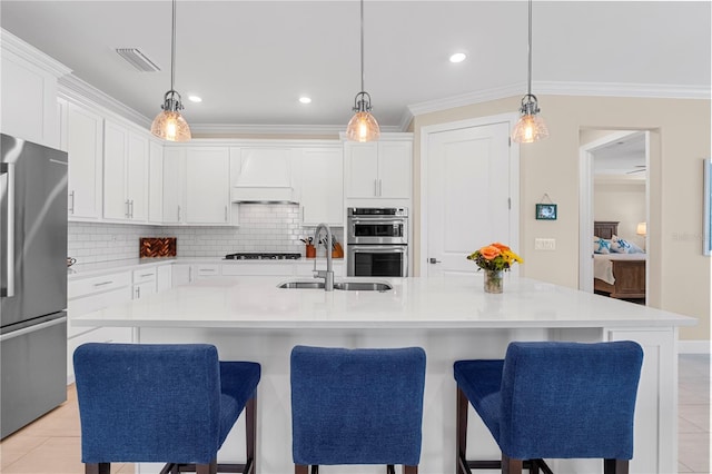 kitchen with white cabinets, appliances with stainless steel finishes, sink, and a center island with sink