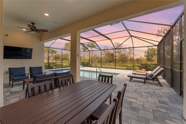 patio terrace at dusk with glass enclosure, an outdoor living space, and ceiling fan