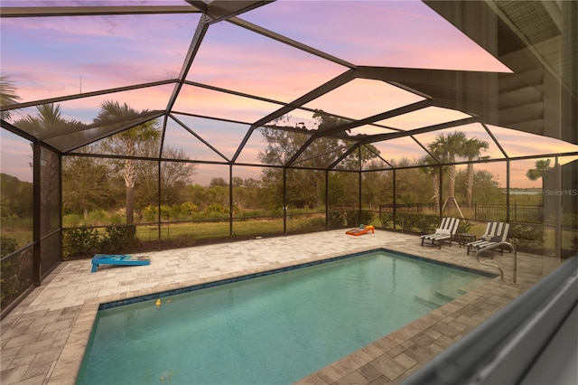 pool at dusk featuring a lanai and a patio area