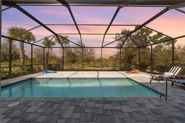 pool at dusk with a patio and glass enclosure