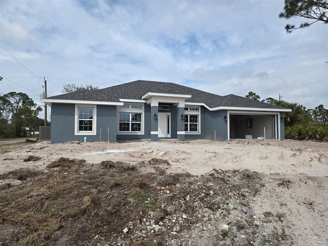 view of front facade with a garage, roof with shingles, and stucco siding